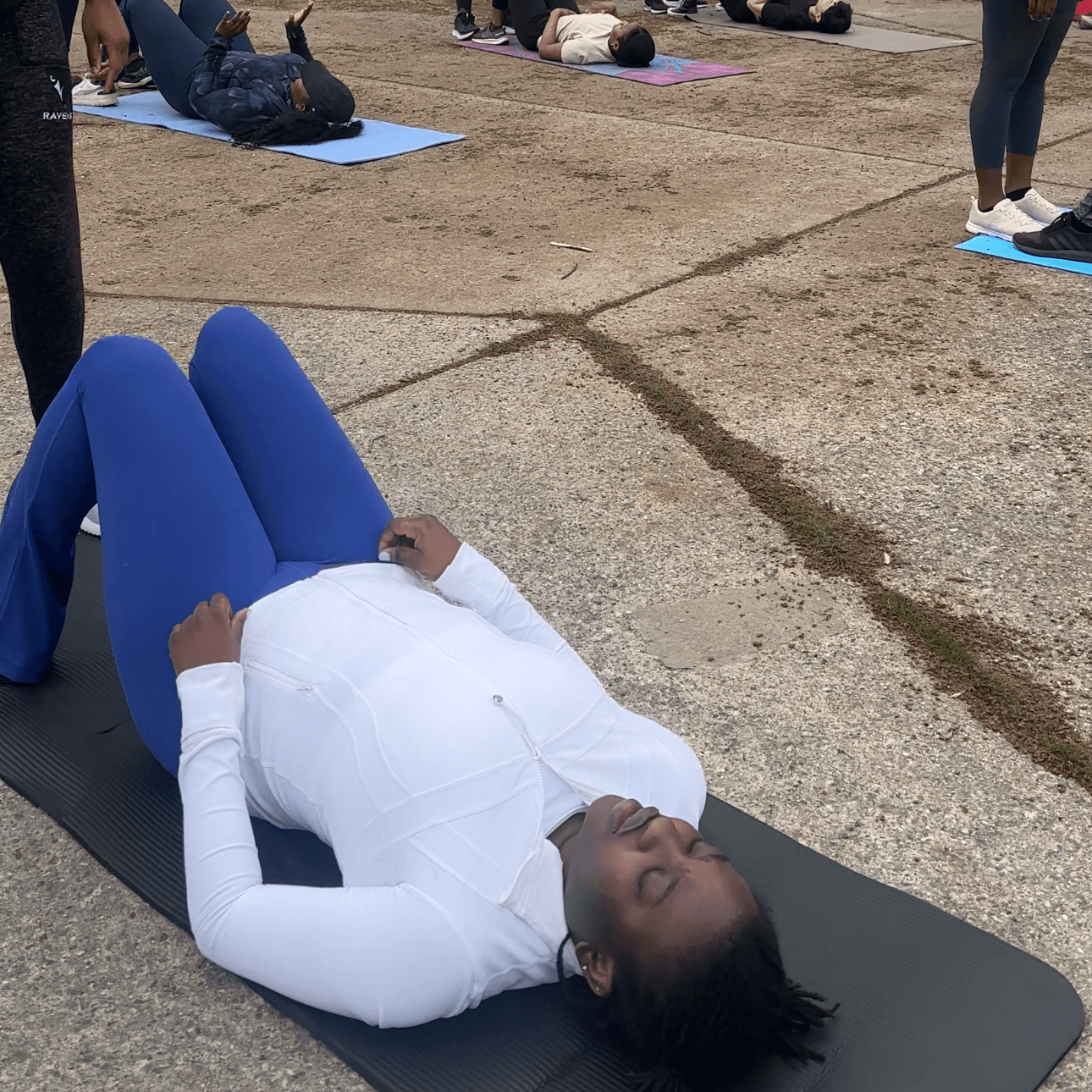 A participant catching her breath on a mat during an outdoor bootcamp